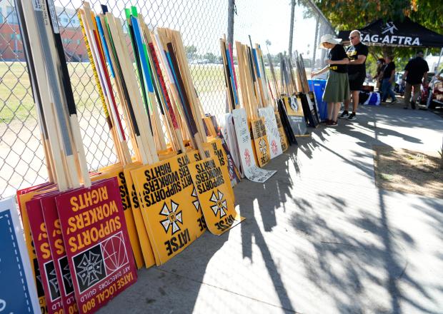 Striking SAG-AFTRA members pick out signs for a picket line...