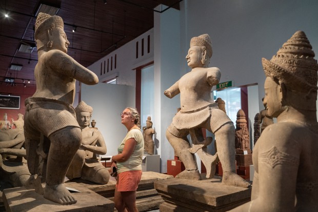 A visitor examines Bhima statue, left, as Duryodhana stands on the right on display inside the National Museum of Cambodia in Phnom Penh Aug. 8, 2022. (Photo by Cindy Liu/Special to The Denver Post)